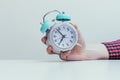 Retro styled white alarm clock in manÃ¢â¬â¢s hand,